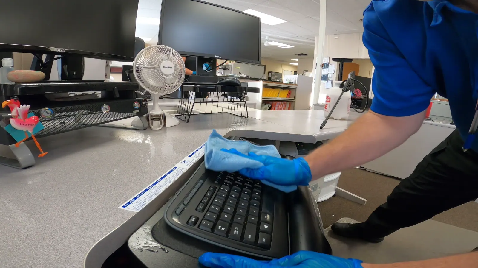 Technician wiping a keyboard at a commercial workstation